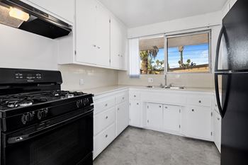 a kitchen with white cabinets and black appliances and a window